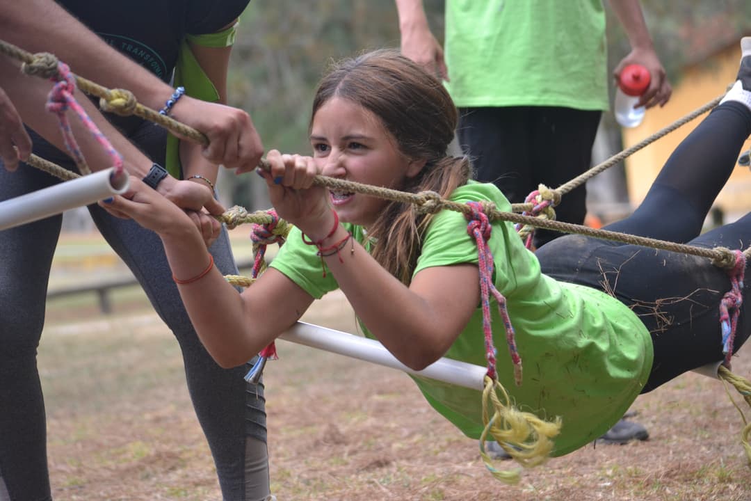Grupo de niños juntando sus manos en señal de unión, reflejando el compañerismo y la integración en el campamento