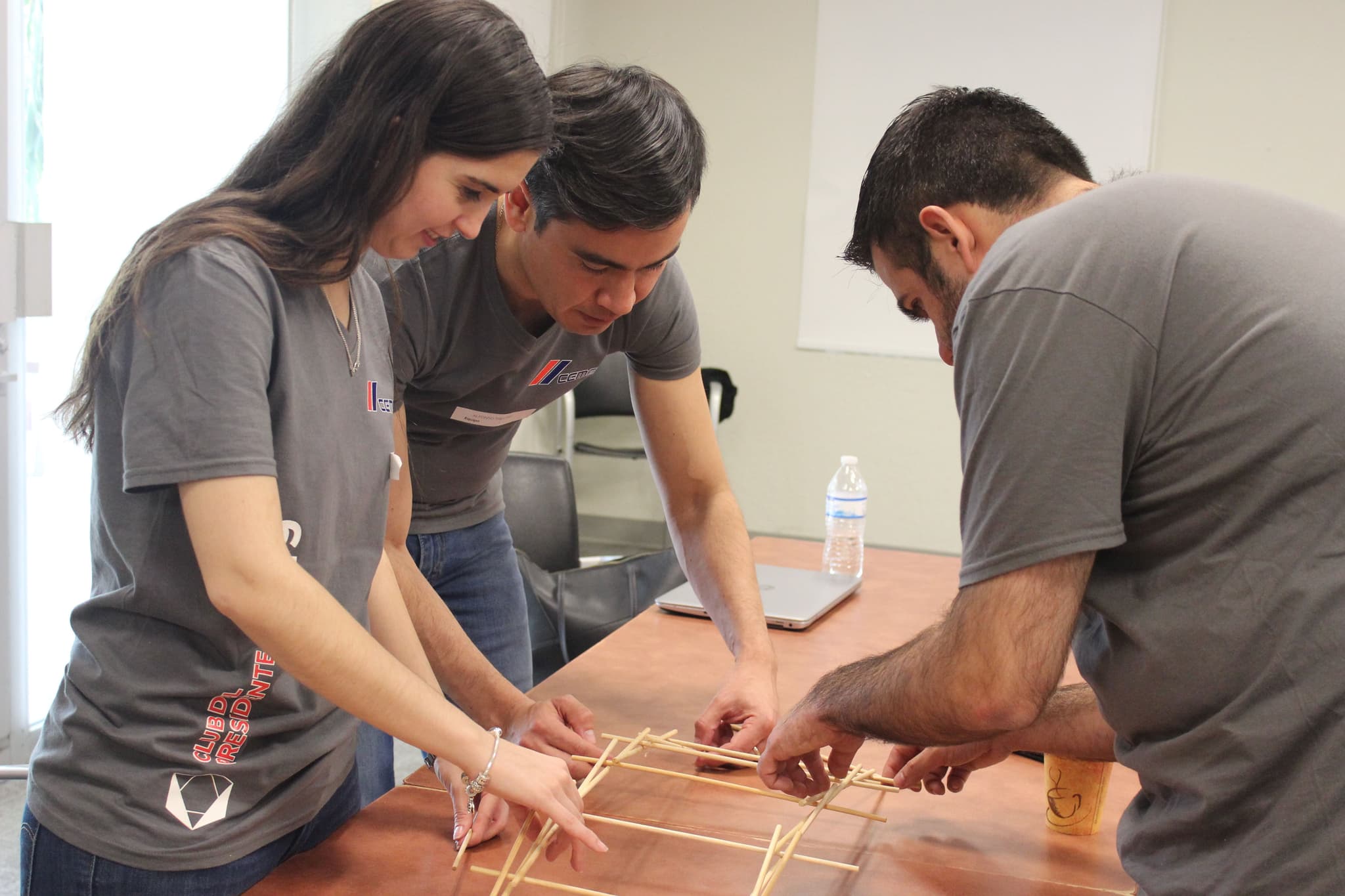 Primer plano de manos ensamblando una estructura de madera, simbolizando creatividad y cooperación en el trabajo en equipo