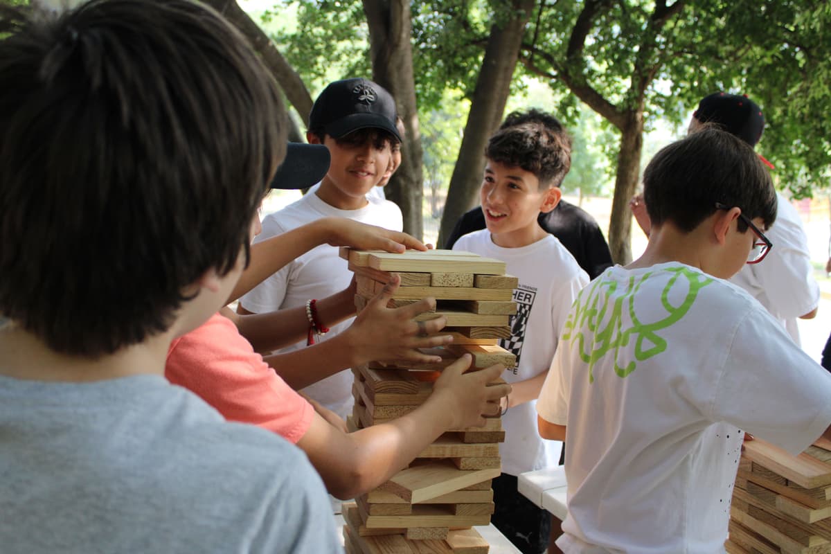 Grupo construyendo una torre de bloques, simbolizando la importancia del trabajo en equipo para lograr metas comunes