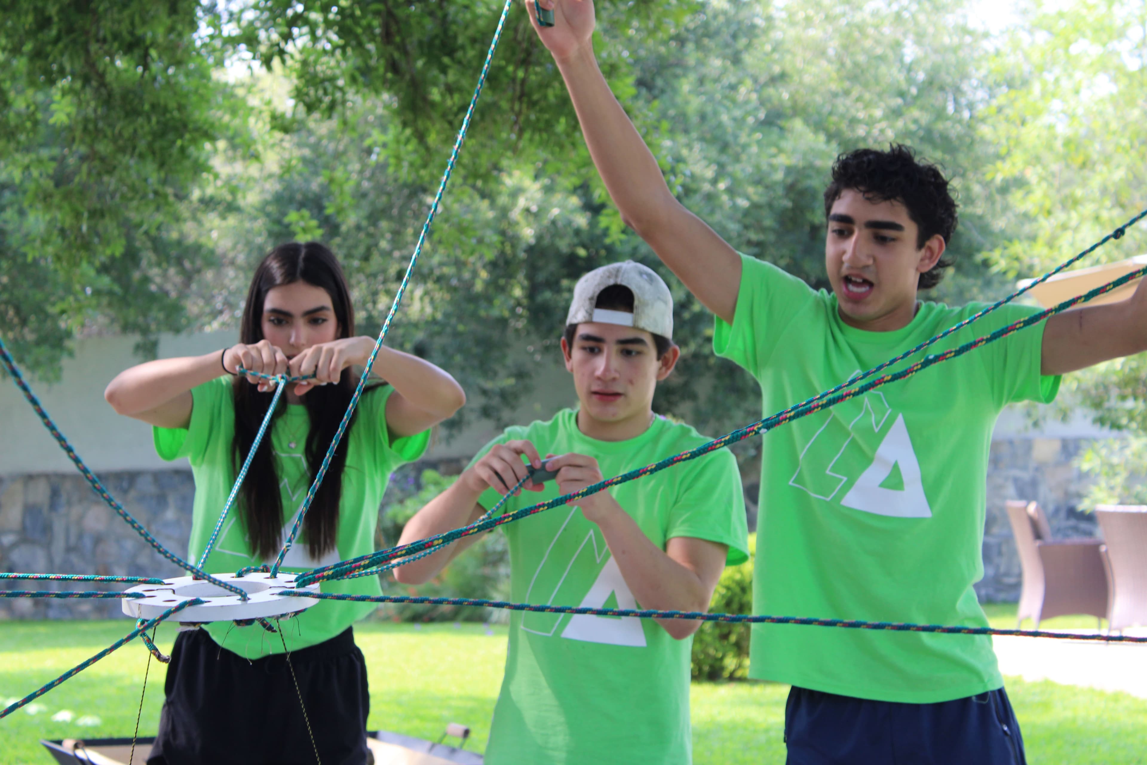 Estudiantes colaborando para superar un desafío de cuerdas, mostrando el impacto del trabajo en equipo en la integración