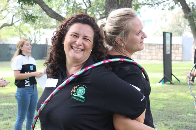 Dos maestras riendo juntas mientras participan en una actividad de integración, destacando la conexión creada durante el evento